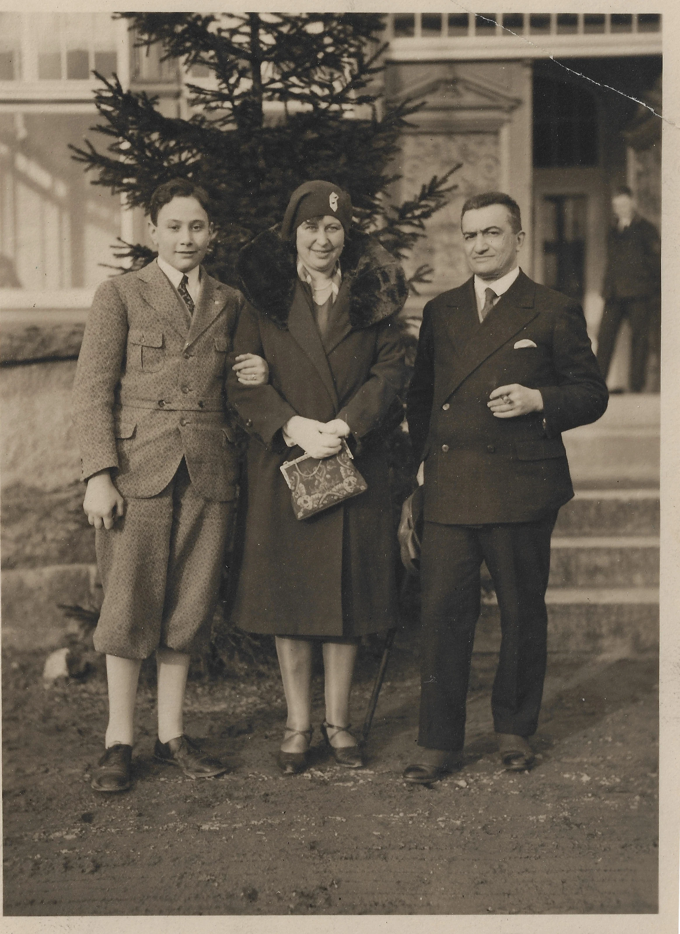 Young Dolf Reichenbach standing beside his mother Margarete and father Paul outdoors